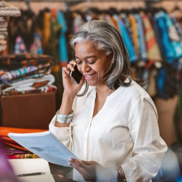 A clothing store owner on her phone in her shop, guided by Carlile, Patchen & Murphy LLP's comprehensive business law services.